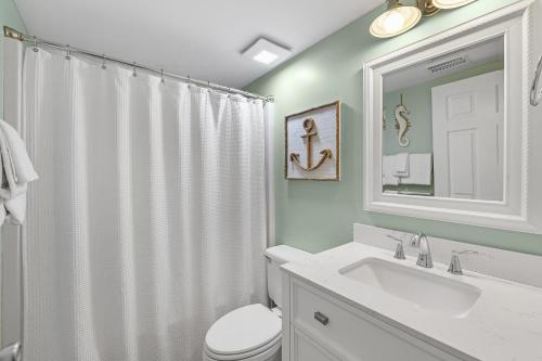a bathroom with a toilet and a sink and a mirror at Tradewinds Unit 608 in Orange Beach