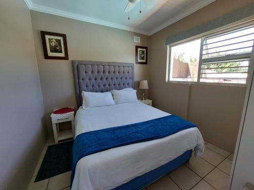 ein Schlafzimmer mit einem großen Bett und einem Fenster in der Unterkunft Poolside Guest House in Port Shepstone