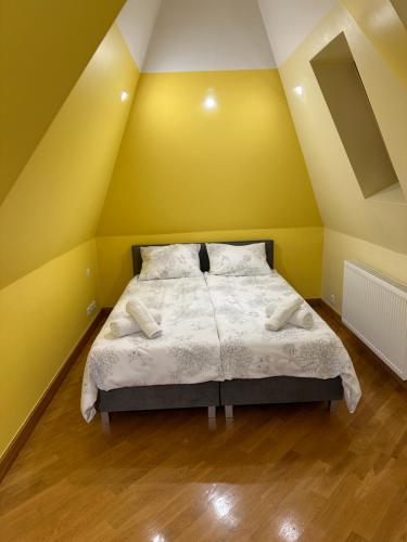 a bedroom with a bed with yellow walls and wooden floors at Villa Sophie in Żabno