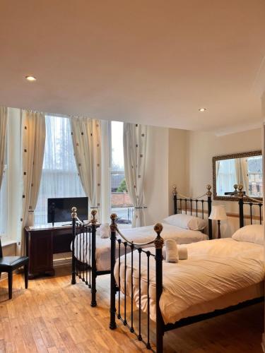 due letti in una camera da letto con scrivania e camino di Sheil Suites a Liverpool