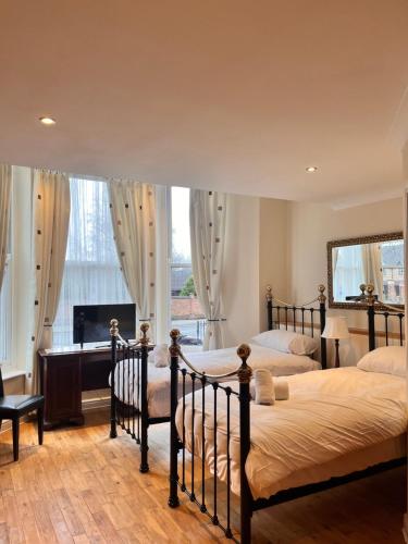 two beds in a bedroom with a desk and a fireplace at Sheil Suites in Liverpool