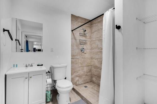 La salle de bains blanche est pourvue d'une douche et de toilettes. dans l'établissement Tropical Oasis Miami Pool Haven, à Miami Gardens