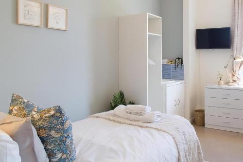 a white bedroom with a bed and a dresser at Poole Park House in Poole
