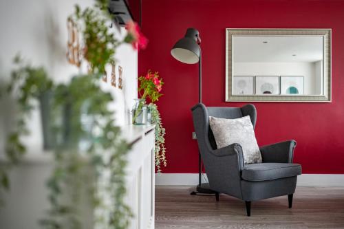 a chair in a living room with a red wall at Brighton Holiday Village PARKING AVAILABLE in Brighton & Hove