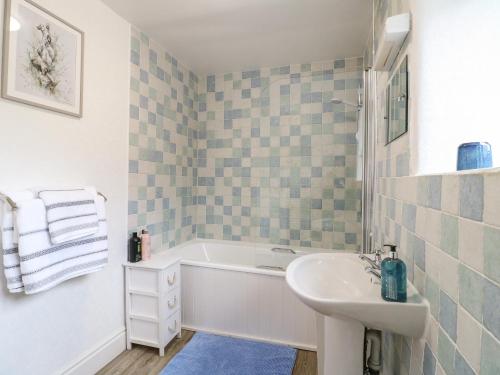 a bathroom with a bath tub and a sink at Toad Cottage in Matlock