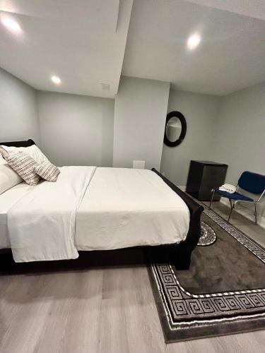 a bedroom with a large white bed and a chair at SUITE A 2 Bedroom Apartment in Brampton