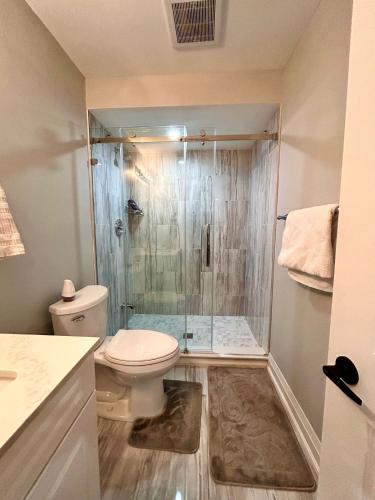 a bathroom with a toilet and a glass shower at SUITE A 2 Bedroom Apartment in Brampton