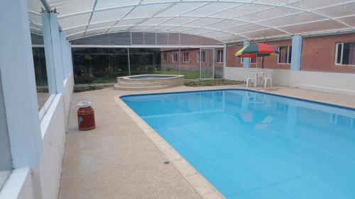 una gran piscina azul en un edificio con sombrilla en HOSTERIA RANCHO SANTA FE en Cotacachi