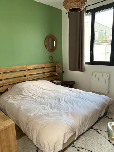 une chambre avec un lit avec une tête de lit en bois et une fenêtre dans l'établissement Appartement spacieux à Asnières-sur-Seine avec terrasse., à Asnières-sur-Seine