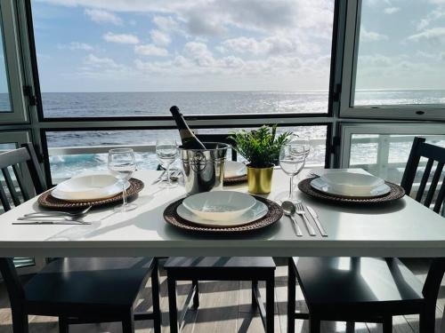 un tavolo con piatti, bicchieri da vino e l'oceano di La Terraza del Mar a Puertito de Güímar