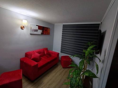 a living room with a red couch and a plant at Lindo y cómodo departamento a pasos del metro in Santiago