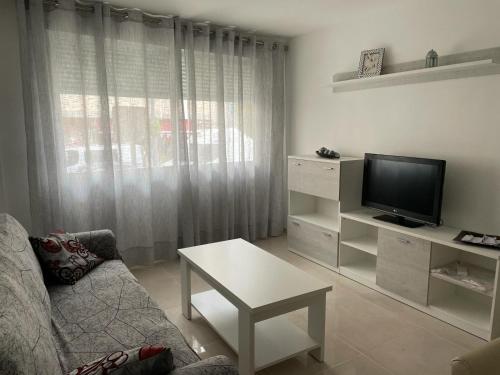 sala de estar con sofá y TV en Apartamento Islu, en Peñíscola