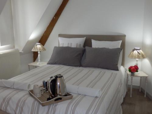 a bed with a tray with a tea kettle on it at Au Presbytère de Dagmar in Erbrée