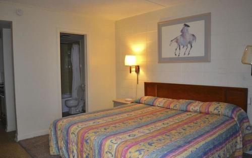 1 dormitorio con 1 cama con un cuadro de caballos en la pared en SeaGypsy Motel, en Myrtle Beach