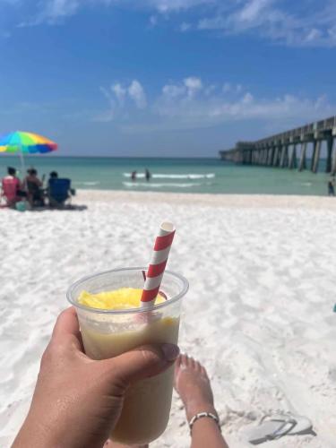 a person holding a drink in front of the beach at Emerald Oasis at Laguna Haven in Panama City Beach