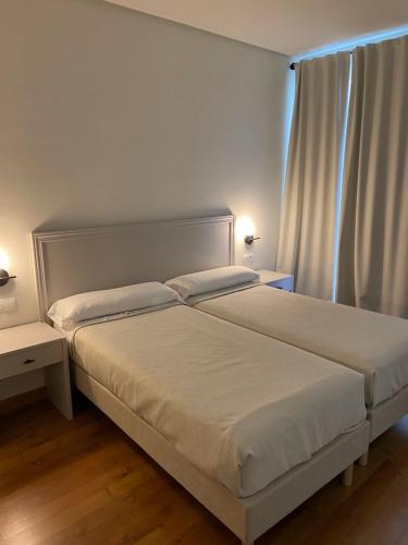 a bedroom with a bed with white sheets and a window at Hotel Santa Ana in La Carlota