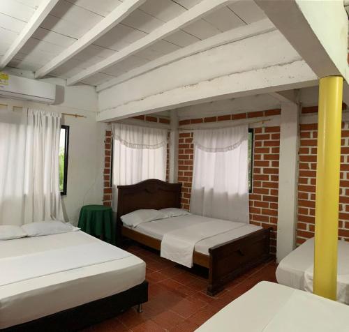 1 dormitorio con 2 camas y pared de ladrillo en CABAÑA VILLA DEL COCO, en Arboletes