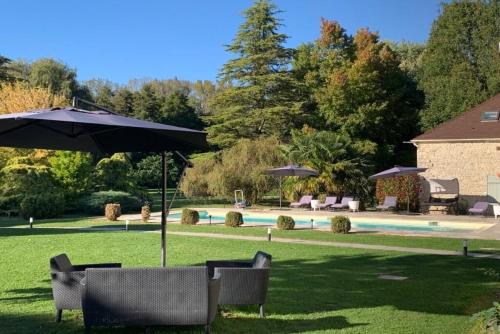 eine Gruppe von Stühlen unter einem Sonnenschirm neben einem Pool in der Unterkunft Domaine des rives d'Ormoy - Athamante in Ormoy-la-Rivière