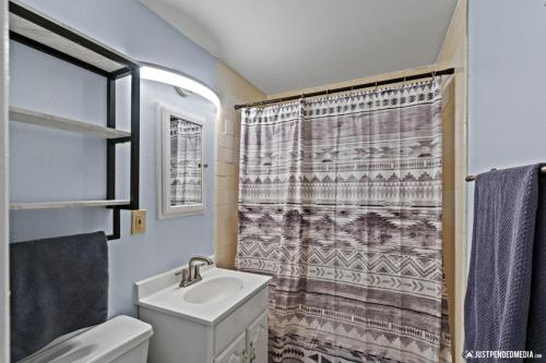 a bathroom with a sink and a shower curtain at White Raven Perch Westwood 6 in Anchorage