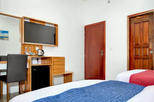 a hotel room with a bed and a desk with a television at Manta Sky Inn in Dharavandhoo