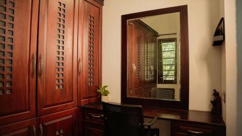 a mirror in a room with a desk and a chair at Marari Sailor Homestay in Shertallai