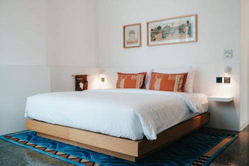 a bedroom with a large white bed with orange pillows at Shada Hotel - فندق شدا in Dubai