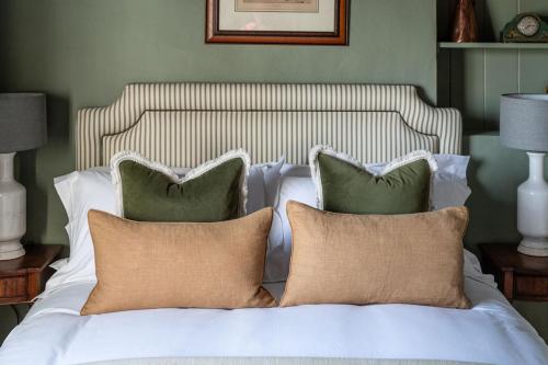 a white bed with three pillows on top of it at Martin Arms in Colston Bassett