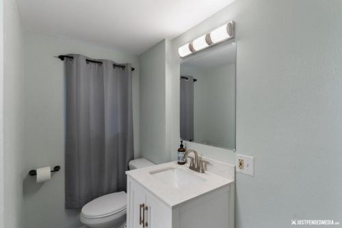 a bathroom with a sink and a toilet and a mirror at Borealis Barnhouse - Slumber 7 in Anchorage
