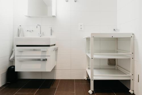 a white bathroom with a sink and a shelf at Apartment Fortaleza in Amden