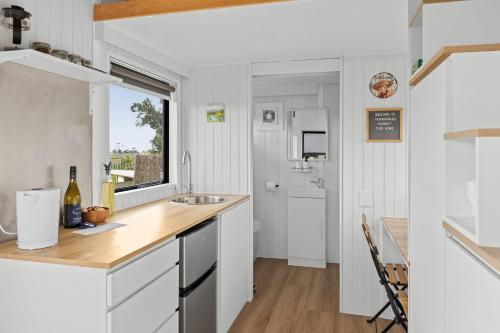 uma cozinha com armários brancos, um lavatório e uma janela em Tataraimaka Farmlet em Tataraimaka