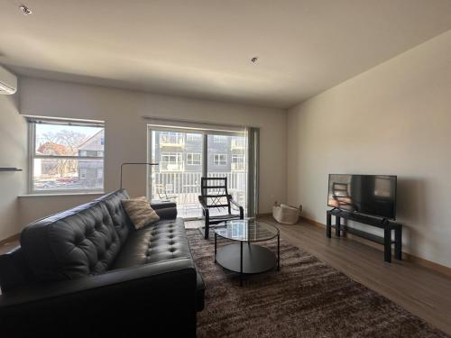 uma sala de estar com um sofá de couro e uma televisão em Flexhome East Side 1BR R2 - Brady Fiserv Balcony - READ INFO em Milwaukee
