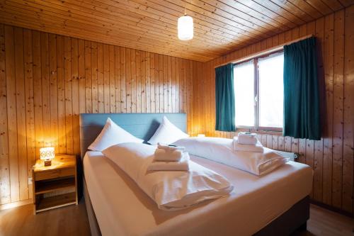 Schlafzimmer mit einem Bett mit weißer Bettwäsche und einem Fenster in der Unterkunft Apartment Bergdohle in Amden