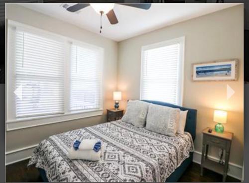 a bedroom with a bed with two pillows and two windows at Cozy Crab Pad in Galveston