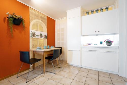 kuchnia z pomarańczowymi ścianami oraz stołem i krzesłami w obiekcie Apartment Mariahalden w mieście Weesen