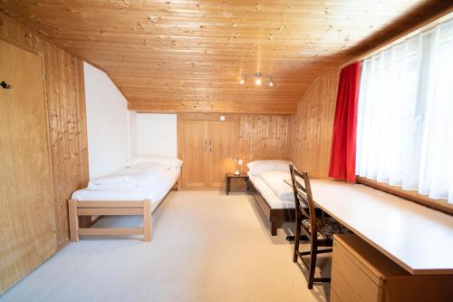 two beds in a room with wooden walls and windows at Chalet Chapfwald in Amden