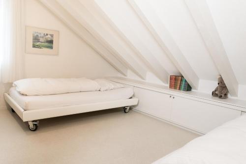 Apartment Hinterberg في امدن: غرفة نوم علوية بيضاء مع سرير ومقعد