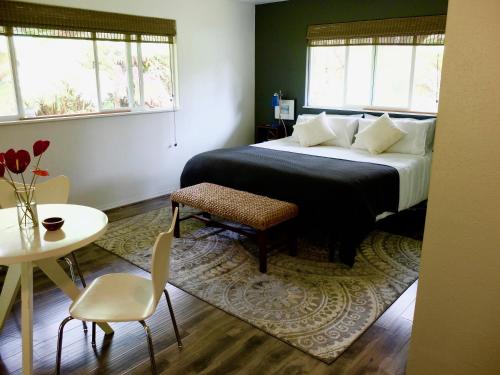 a bedroom with a bed and a table and chairs at Volcano One - Modern Studio with Lanai near Volcano National Park in Volcano