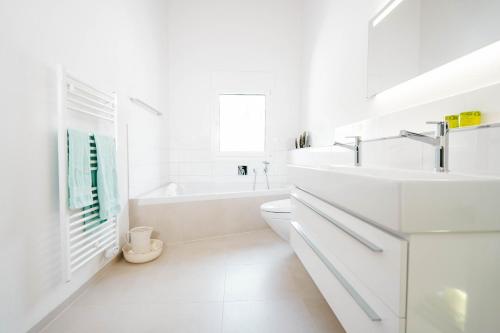 a white bathroom with a tub and a sink at Apartment Soldanella in Amden