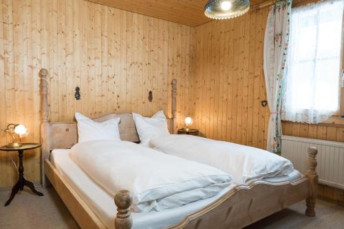 a bedroom with a bed with white sheets and a window at Chalet Theresia in Amden