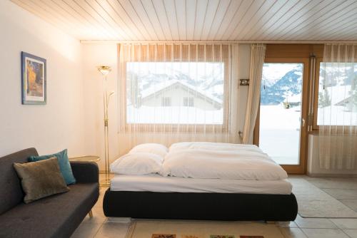 Bett in einem Zimmer mit Sofa und Fenster in der Unterkunft Apartment Grossgaden in Amden