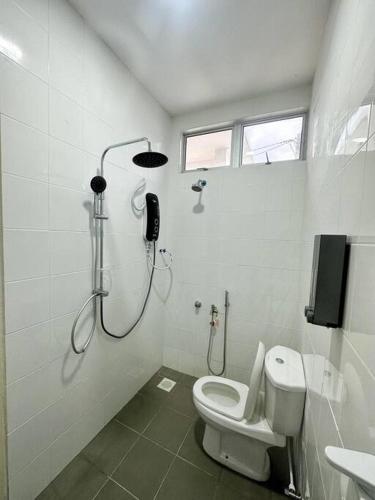 een witte badkamer met een douche en een toilet bij D'Banggol Homestay in Ketereh