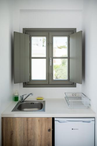 a kitchen with a sink and a window at Amphitrite Suites Santorini in Vóthon