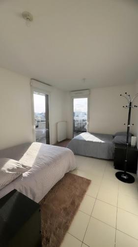 two beds in a white room with windows at Chambres sur Cergy in Cergy