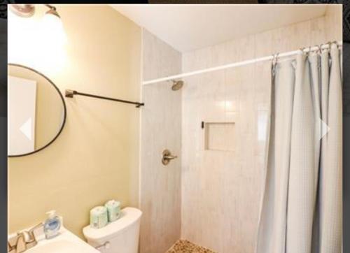 a bathroom with a shower and a toilet and a mirror at Old Bay All Day in Galveston