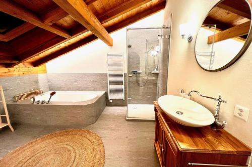 a bathroom with a tub and a sink and a mirror at Apartment zum Leist in Amden
