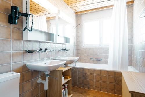 La salle de bains est pourvue de 2 lavabos, d'une baignoire et d'une fenêtre. dans l'établissement Apartment Bischofberger D22, à Amden