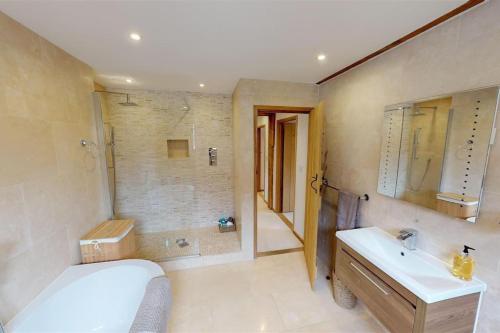 een badkamer met een bad, een wastafel en een douche bij Home in Virginia Water in Wentworth