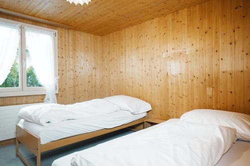 - 2 lits dans une chambre avec un mur en bois dans l'établissement Apartment im Chalet Biodola, à Amden