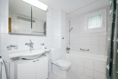 La salle de bains blanche est pourvue d'un lavabo et de toilettes. dans l'établissement Apartment im Chalet Biodola, à Amden