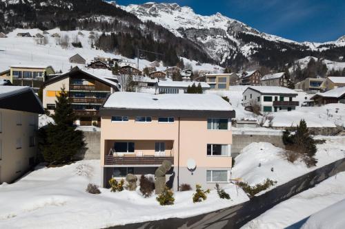 a building in the snow with mountains in the background at Apartment Im Aeschen in Amden